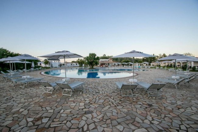 Piscina con lettini e ombrelloni grigi.