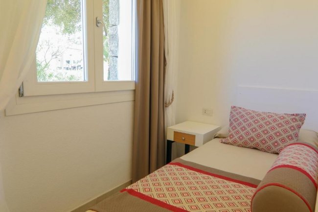 Letto singolo vicino a finestra luminosa.