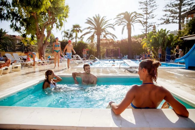Persone in piscina e vasca idromassaggio all'aperto.