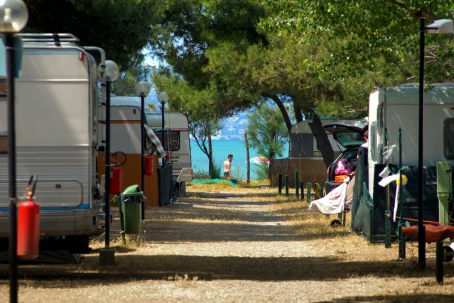 Caravan e tettoie ai lati di un sentiero con vista sul mare.