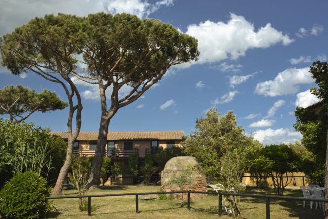 Giardino con alberi e cespugli, edificio in mattoni con un tetto a tegole.