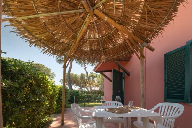 Patio con tavolo e sedie sotto un tetto di paglia.