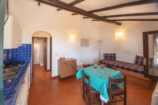 Cucina con tavolo e divano sotto travi a vista.
