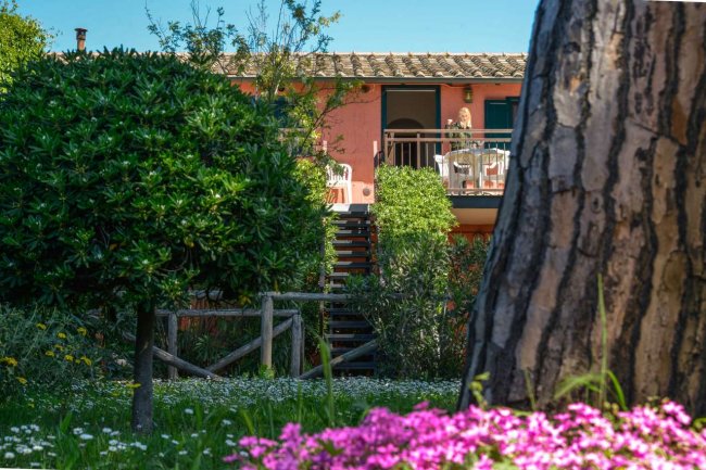 Edificio rosa con balcone e giardino fiorito.