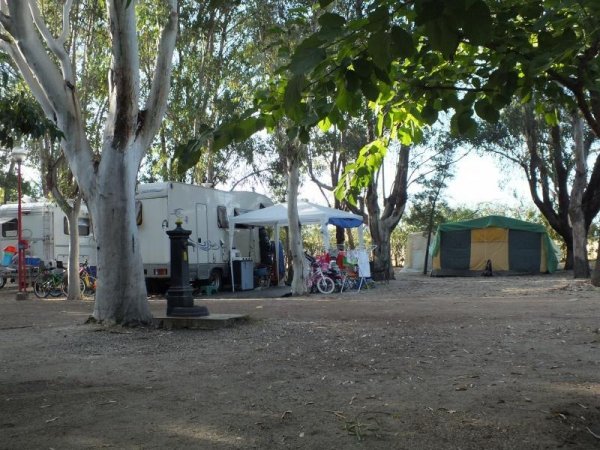 Caravan e tenda con area picnic tra gli alberi.