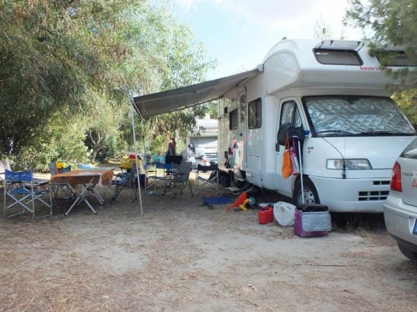 Camper parcheggiato con tavoli e sedie fuori.