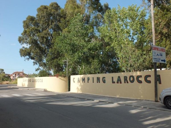 Ingresso del camping La Rocca con scritta su muro giallo.