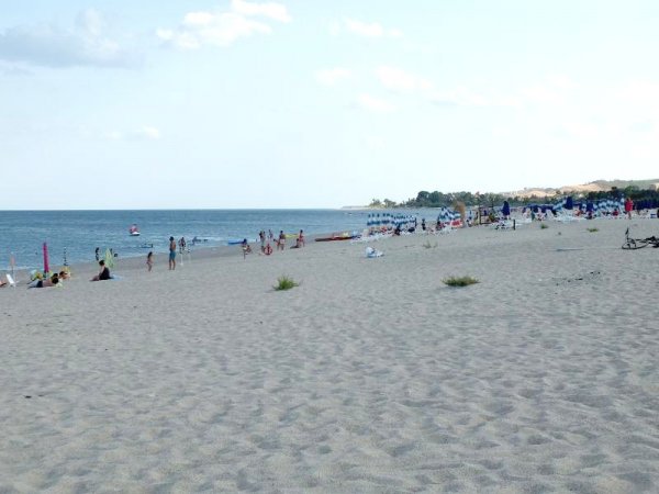 Lunga spiaggia sabbiosa con bagnanti distanti.
