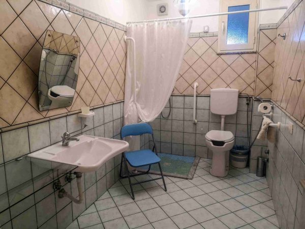 Bagno accessibile con doccia e sedia pieghevole.