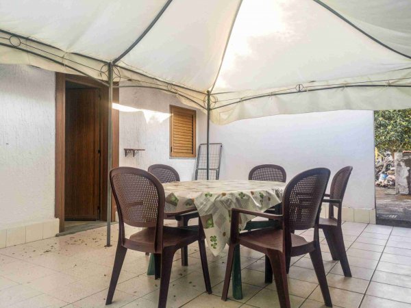 Tavolo sotto gazebo con sedie marroni.