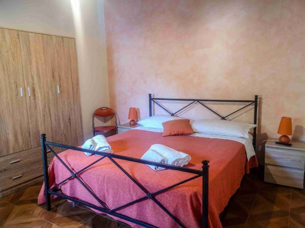 Camera da letto con letto matrimoniale, coperte arancioni e armadio.