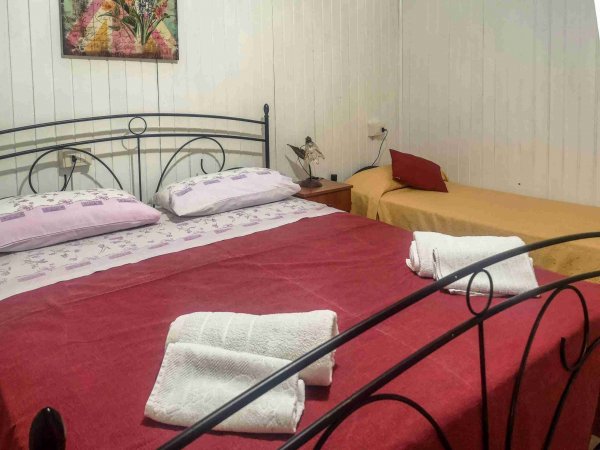 Camera con letto matrimoniale e singolo, pareti bianche.