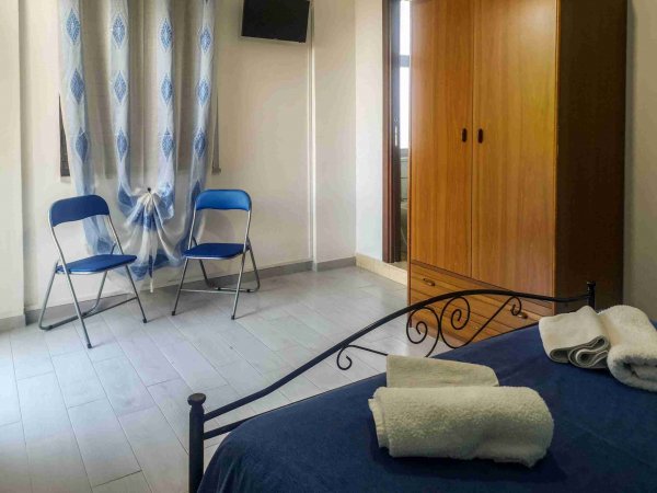 Camera con letto, armadio, due sedie e una TV.