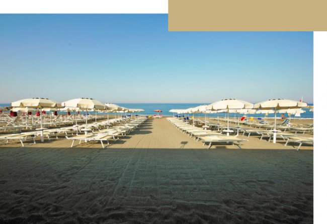 Spiaggia con lettini e ombrelloni bianchi.