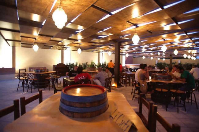 Interno di un ristorante con tavoli in legno e clienti seduti.