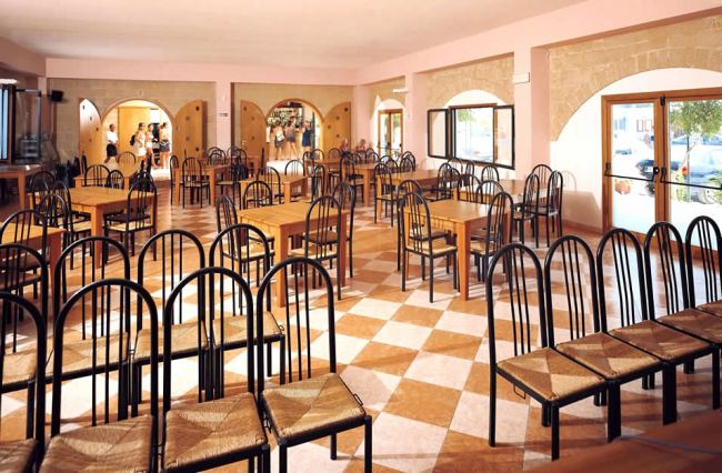 Ristorante vuoto con sedie nere e tavoli in legno.