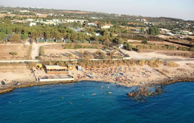 Spiaggia affollata con ombrelloni e mare azzurro.
