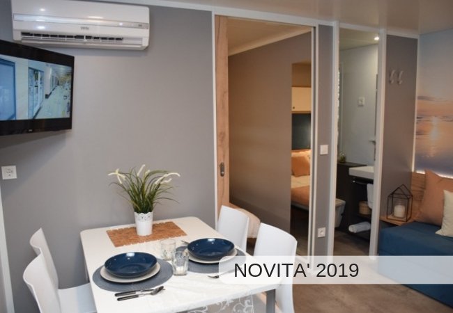 Sala da pranzo moderna con tavolo apparecchiato e TV.