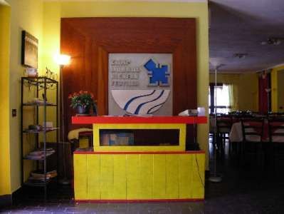 Reception con scrivania gialla e insegna blu su sfondo giallo.