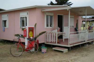 Casetta rosa con veranda bianca e bicicletta rossa parcheggiata davanti.