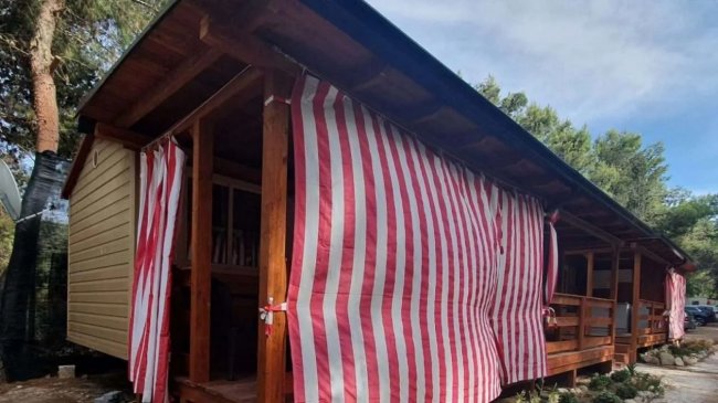 Bungalow in legno con tende a strisce rosse e bianche.