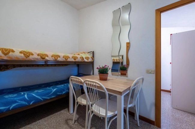 Letto a castello, tavolo con sedie e specchiere ondulate.