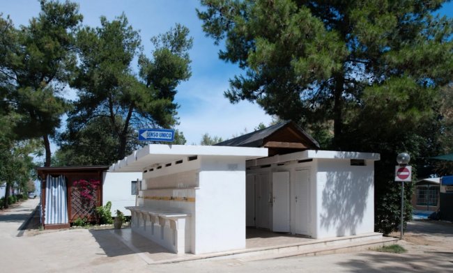 Un edificio bianco con cartello blu e piante intorno.