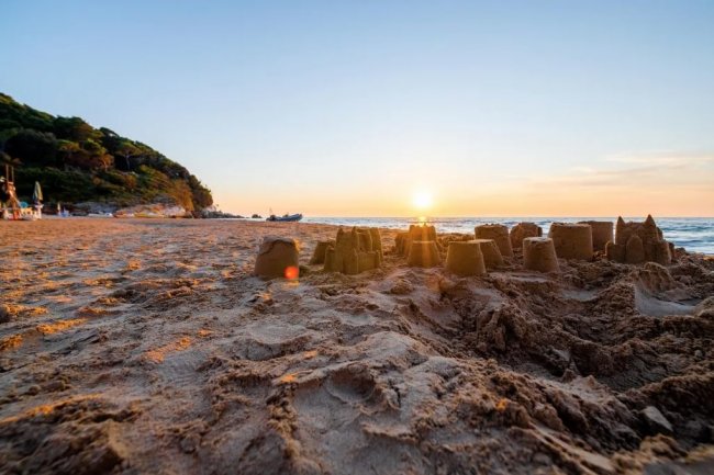 Castelli di sabbia su una spiaggia al tramonto.