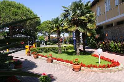 Giardino con aiuole di fiori e palme vicino a un edificio giallo.