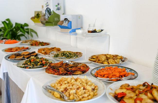 Tavolo buffet con piatti di verdure, patate e altri contorni.