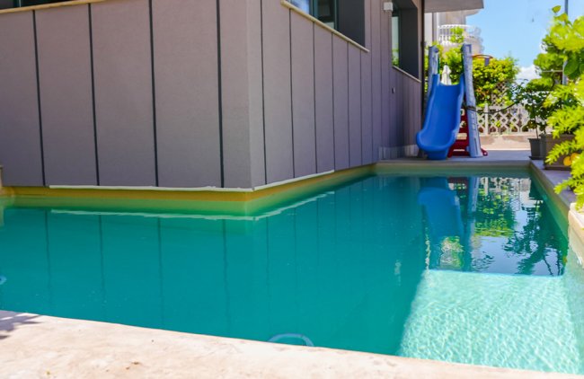 Piscina con scivolo blu accanto a un edificio moderno.