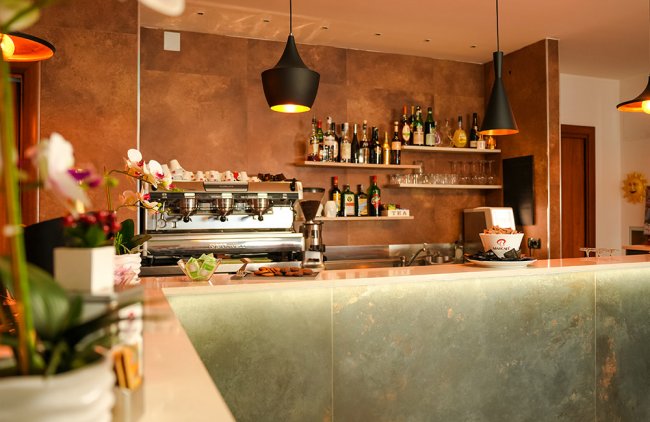 Dettaglio del bancone del bar con macchina da caffè e luci pendenti.