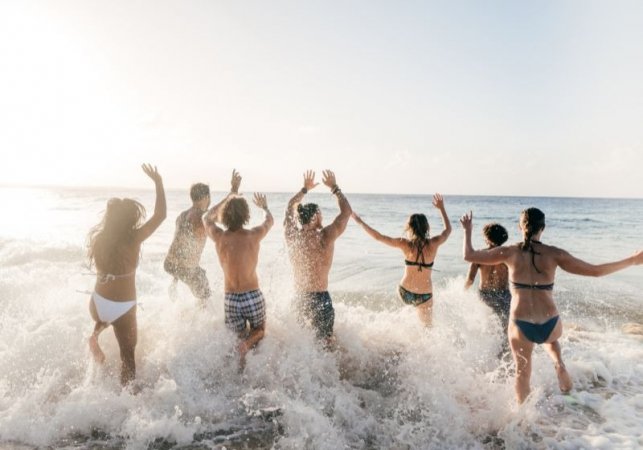 Persone che corrono nel mare con entusiasmo al tramonto.