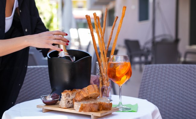 Snack con pane, grissini e cocktail su un tavolo all'aperto.