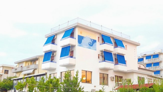 Edificio bianco con tende blu sulle finestre, decorazione a murale con tema marino.