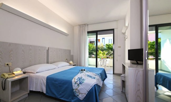 Camera d'hotel con letto matrimoniale e balcone.