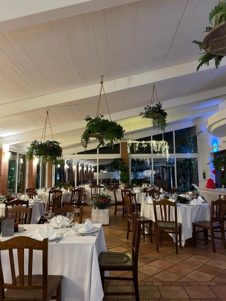 Ristorante elegante con tavoli apparecchiati e piante appese.