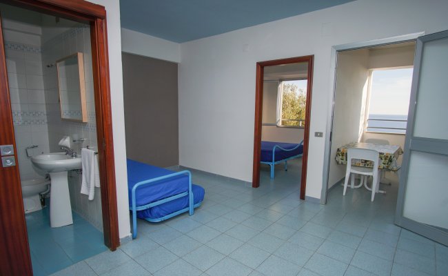 Stanza con letti blu e vista mare.