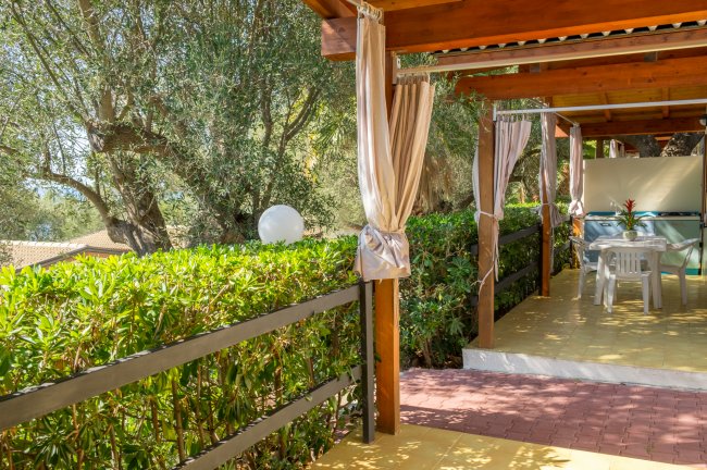 Veranda con tavolo bianco, circondata da siepi.