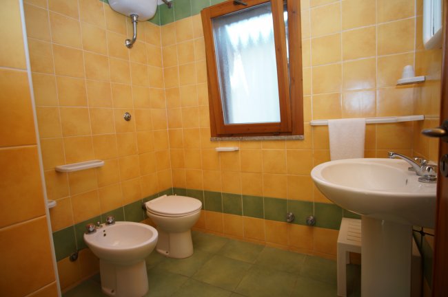 Bagno con piastrelle gialle e verdi, bidet e lavabo.