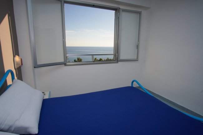 Letto singolo vicino a una finestra sul mare.