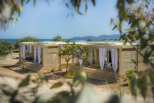 Bungalow in legno vicino al mare, con tende bianche.