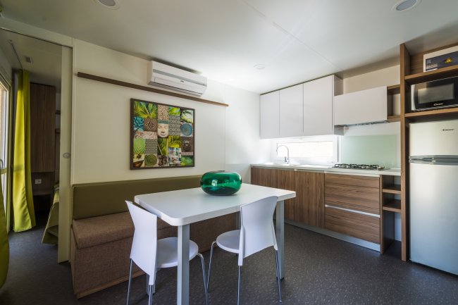 Interni di bungalow con tavolo, sedie e cucina.
