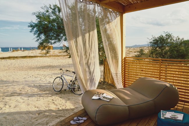 Patio con lettino, bici e tenda, vista sulla spiaggia.