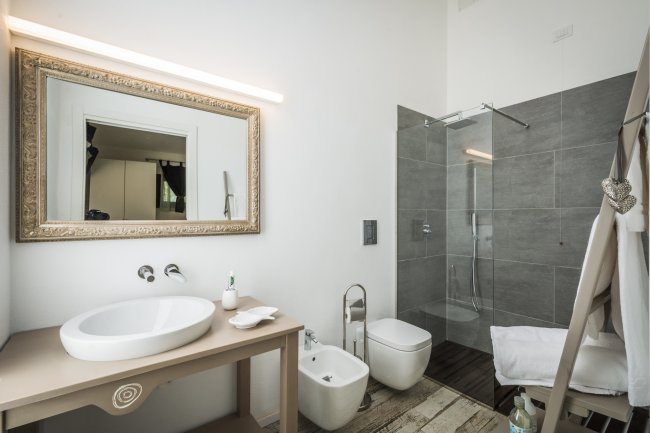 Bagno moderno con doccia, specchio grande e bidet.