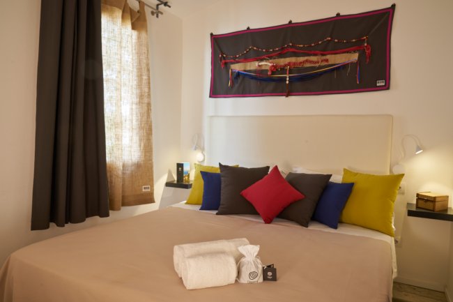 Una camera da letto accogliente con cuscini colorati e asciugamani piegati sul letto.