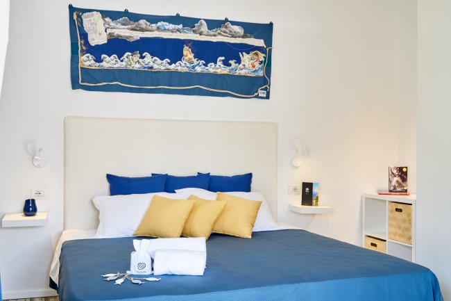 Camera da letto con letto blu e cuscini gialli.