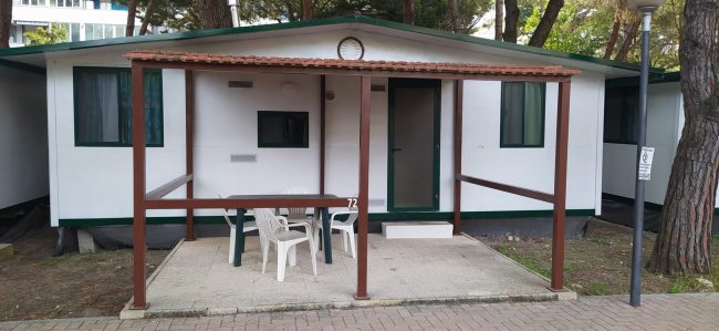 Bungalow bianco con portico e sedie.