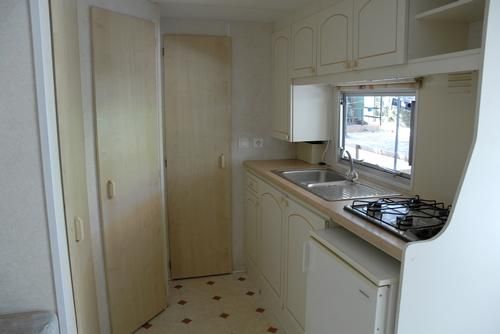 Cucina stretta in una roulotte, con lavello, piano cottura e frigorifero.