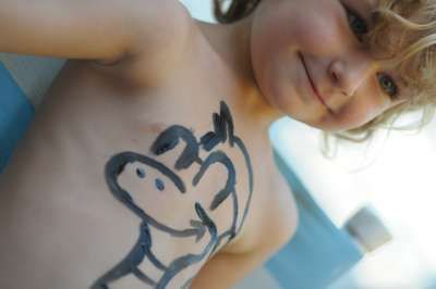 Bambino sorridente con disegno di zebra dipinto sul torace.